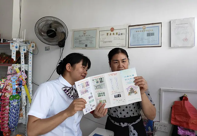 图为:曙光支行工作人员向搬迁点服务点商户讲解假币识别方法.jpg