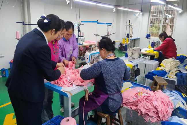 （图为：工作人员走访辖内服装加工厂）.png