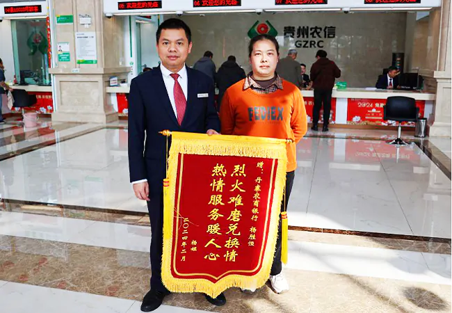 （图为：丹寨农商银行工作人员杨胜恒收到客户的感谢锦旗）.png