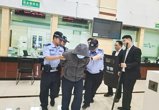 （图为：公安民警与银行工作人员密切配合成功制服歹徒）.png