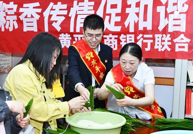 图为：银行工作人员为社区居民包粽子.jpg