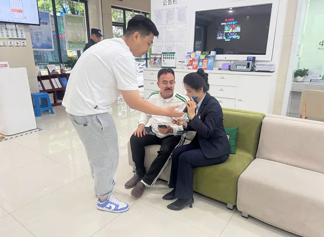 图为:邮储银行黔东南州分行营业部业务人员借助中英文转换APP与外籍客户交流.png