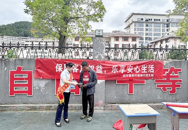 图为：剑河富民村镇银行工作人员向路人发放宣传手册.jpg