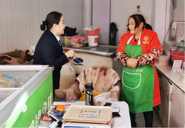 图为:杉木河分社副主任洪玮为商户宣传信贷政策.png