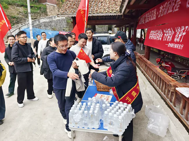 图为：贵州银行工作人员为徒步者免费发放矿泉水并普及反诈金融知识1.png