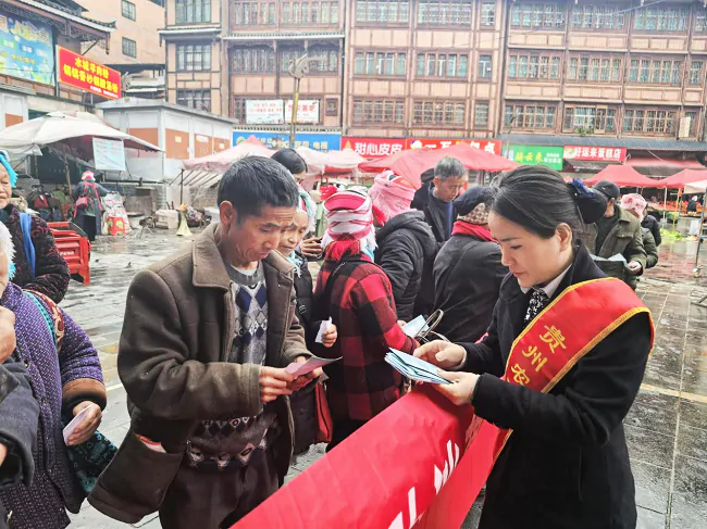 图为：黄平农商银行工作人员在赶集日向群众发放并耐心讲解金融知识宣传折页.png