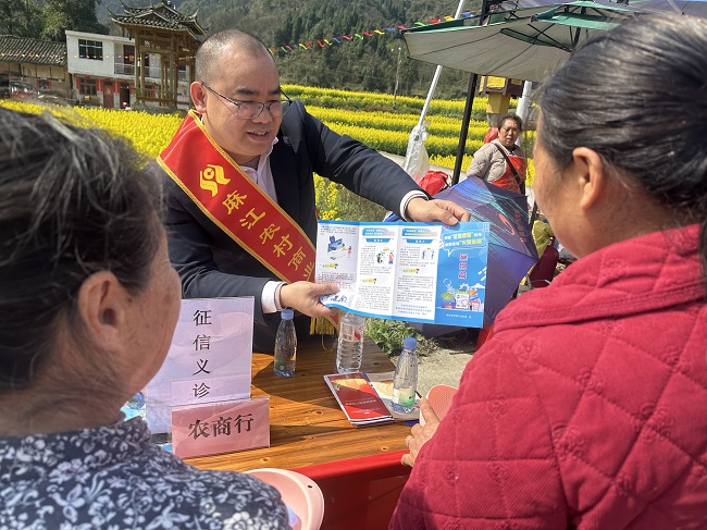 图为：麻江农商银行工作人员向来参加油菜花节客户宣讲金融知识.jpg